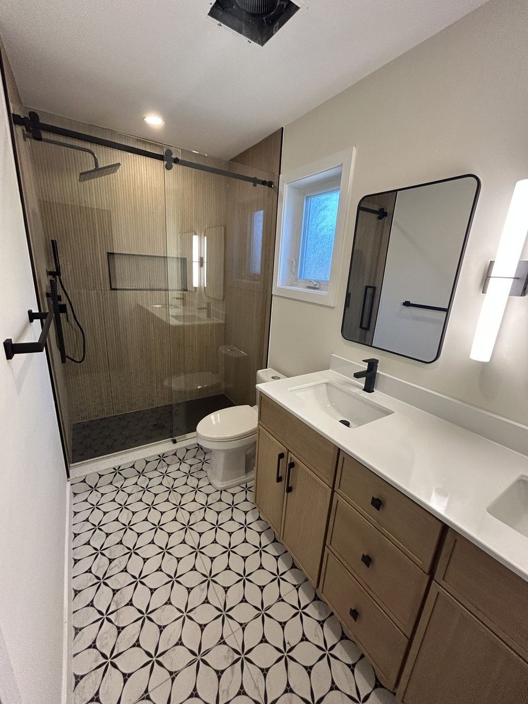 Bathroom with patterned porcelain floor tile and an oak double vanity in Thornhill, by NewGen Renovations Vaughan
