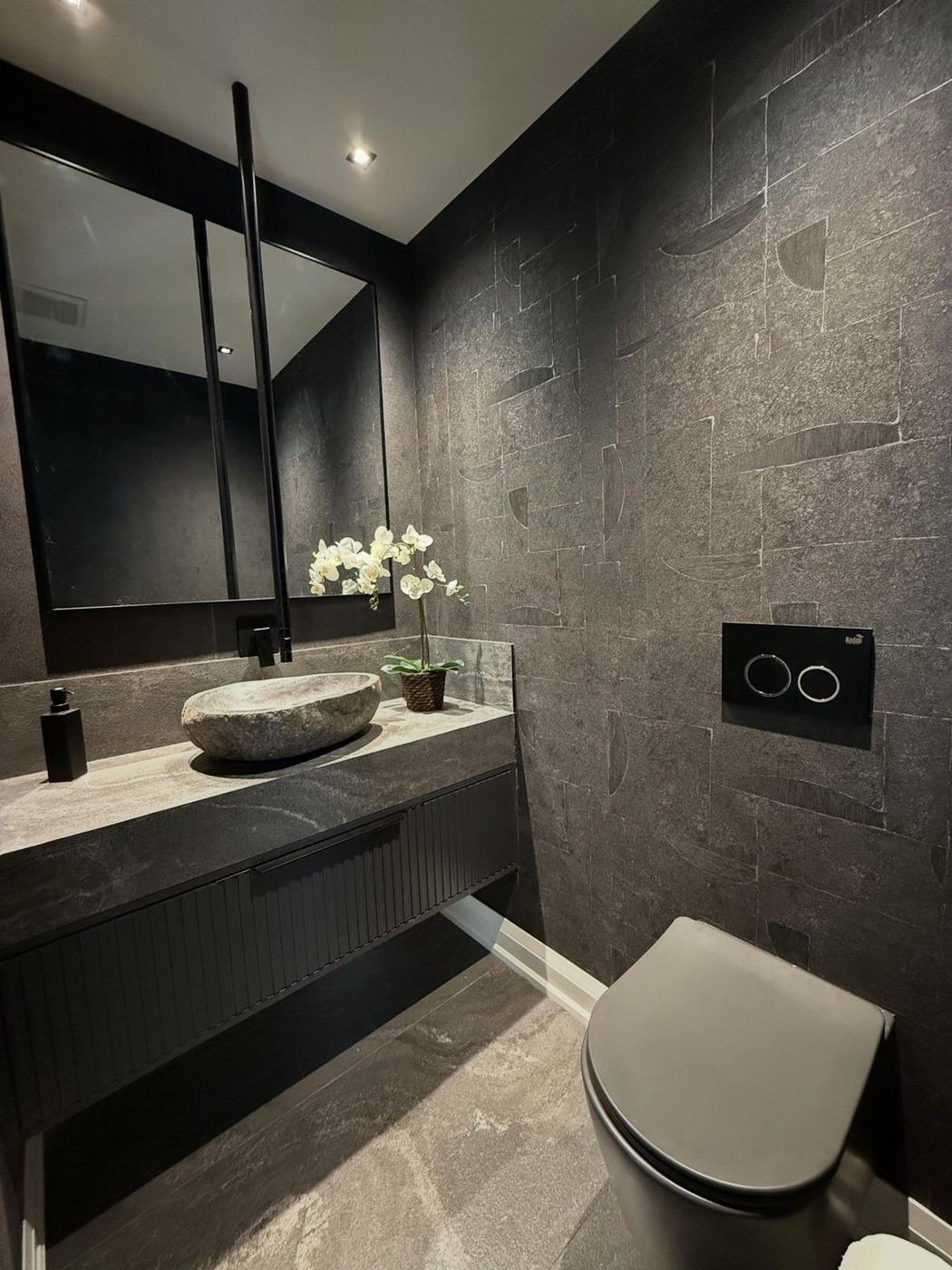 Powder room renovation in Richmond Hill with charcoal stone-look wall tile, a floating fluted vanity with a natural stone vessel sink, black fixtures and a wall-hung toilet, by NewGen Renovations Vaughan
